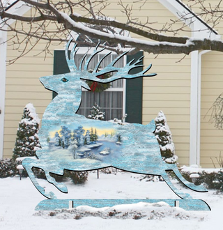 A large, stylized reindeer sculpture stands in the snow in front of a house, with a wreath hanging on the door.