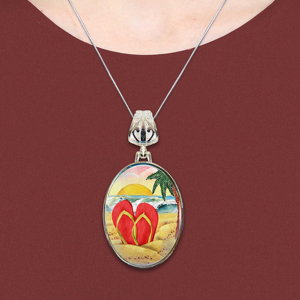 A necklace with a circular pendant featuring a beach scene with a pair of red flip-flops in the foreground.