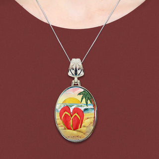 A necklace with a circular pendant featuring a beach scene with a pair of red flip-flops in the foreground.