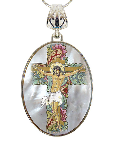 A pendant featuring a religious scene of Jesus Christ crucified, with intricate floral and ornamental designs surrounding the central figure.