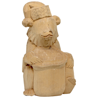 A wooden carving of a bear wearing a hat and holding a drum.