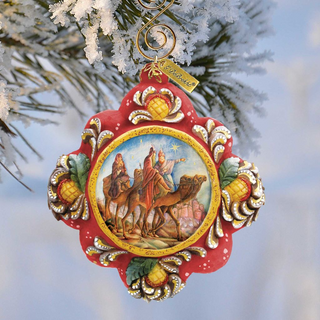 A decorative Christmas ornament featuring a scene of three figures on a camel, with a star in the sky, is hanging on a tree branch.