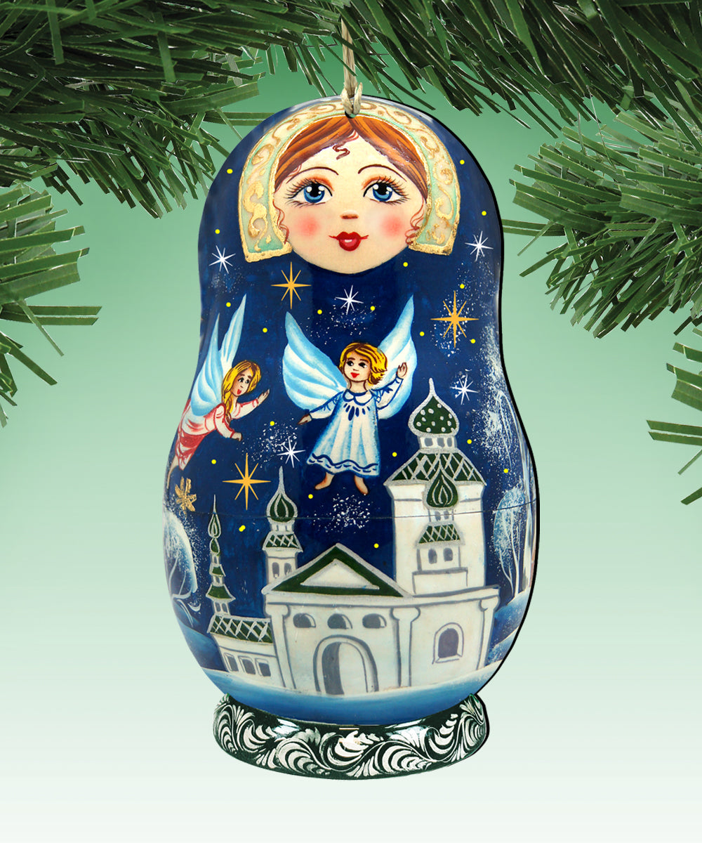 A blue and white nesting doll ornament with a painted face and angel wings, hanging on a tree branch.