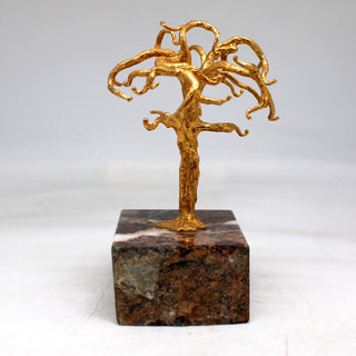 a gold sculpture of a tree on a marble block