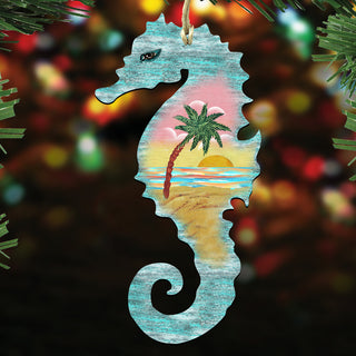 A wooden ornament in the shape of a seahorse, with a tropical beach scene painted on it, is hanging on a Christmas tree.
