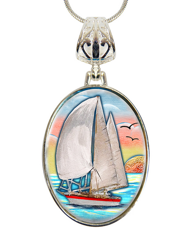 A pendant necklace with a circular oval-shaped design featuring a sailboat on the water, with a sunset in the background.