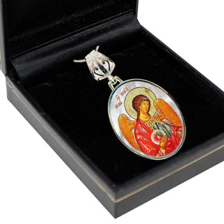 A pendant with an ornate design, featuring a religious icon of a saint or angel, is displayed in a black box.
