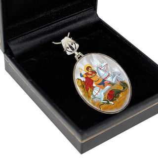 A pendant in a black box, featuring a religious scene with a saint on a horse.