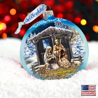 A blue Christmas ornament with a nativity scene depicting the birth of Jesus Christ, featuring the Virgin Mary, baby Jesus, and other figures in a snowy landscape.