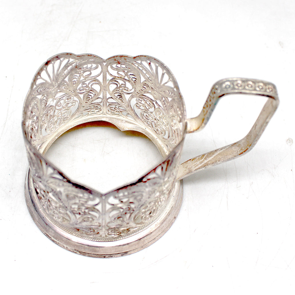 a silver teapot shaped like a heart on a white surface