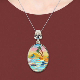 A necklace with a pendant featuring a colorful tropical scene with palm trees, a sunset, and a body of water.