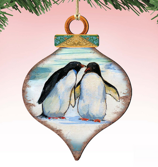 A decorative ornament featuring two penguins standing close together, with a pink background and a green and gold design.