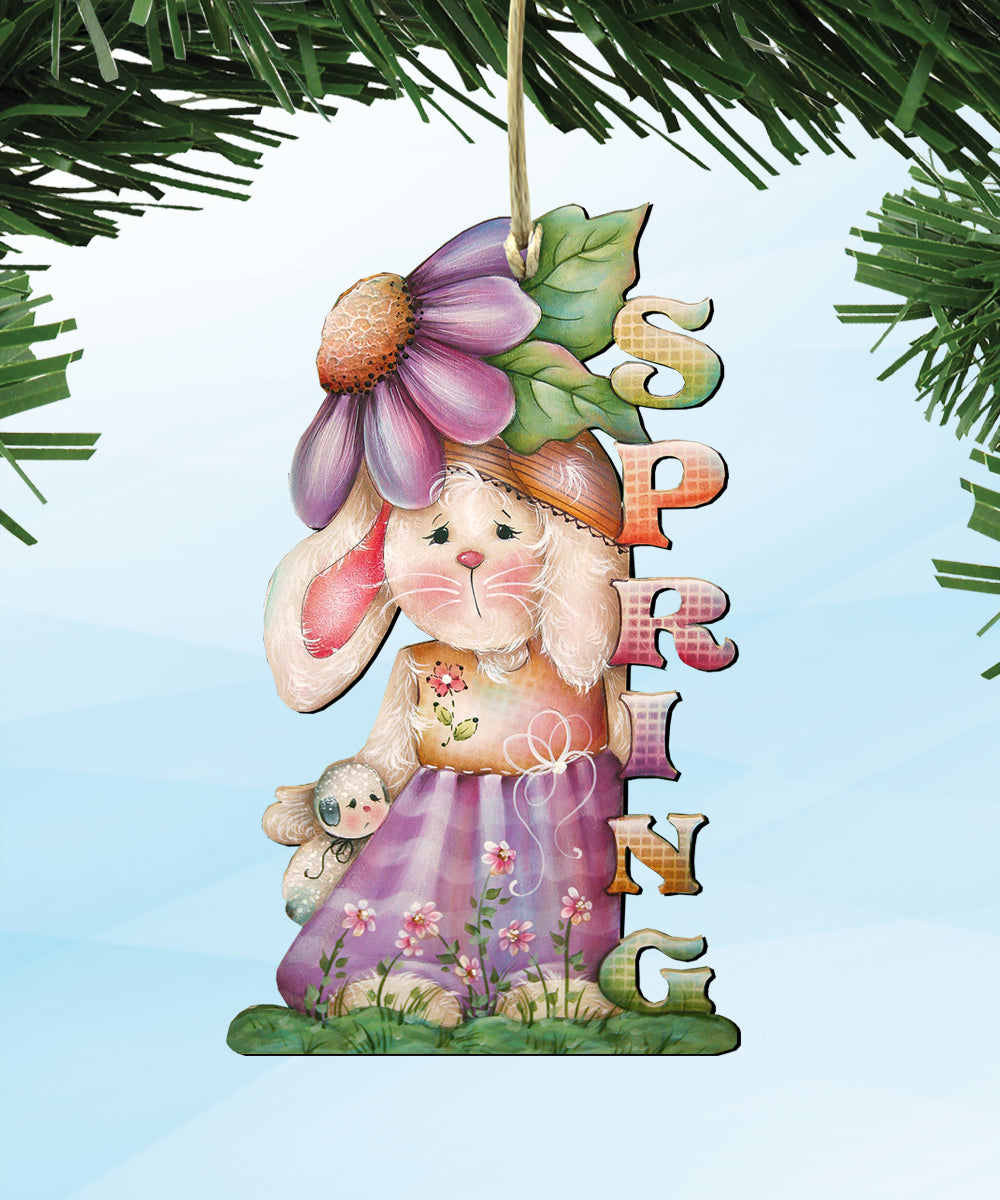 A colorful ornament featuring a bunny wearing a hat and dress, with a flower on its head, and the word