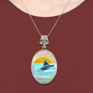 A necklace with a pendant featuring a painting of a dolphin swimming in the ocean.
