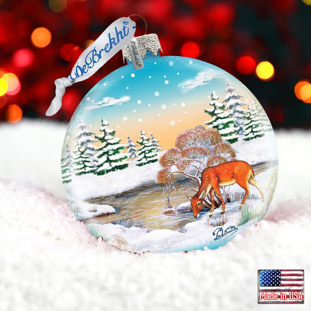 a glass ornament with a picture of a deer in the snow