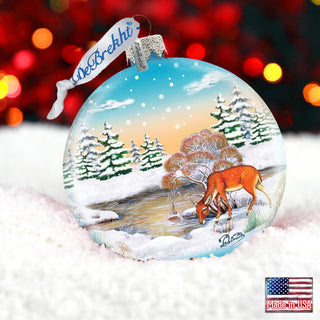 a glass ornament with a picture of a deer in the snow