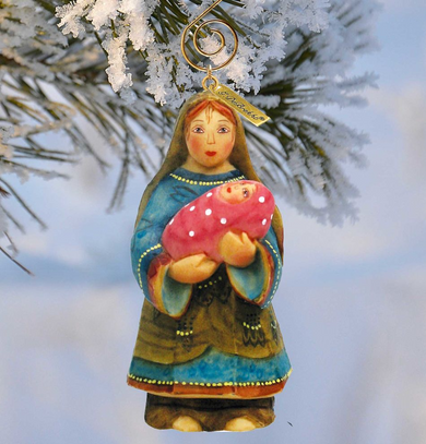 A Christmas ornament depicting a woman holding a baby, with a snowy background.