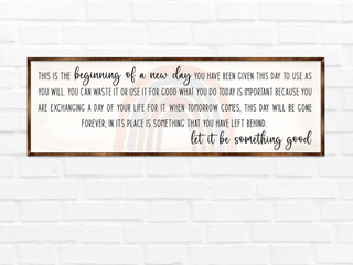 a framed inspirational quote on a white brick wall.