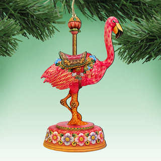 A vibrant, hand-painted ornament of a pink flamingo, featuring intricate details and a decorative base, is displayed against a green background.