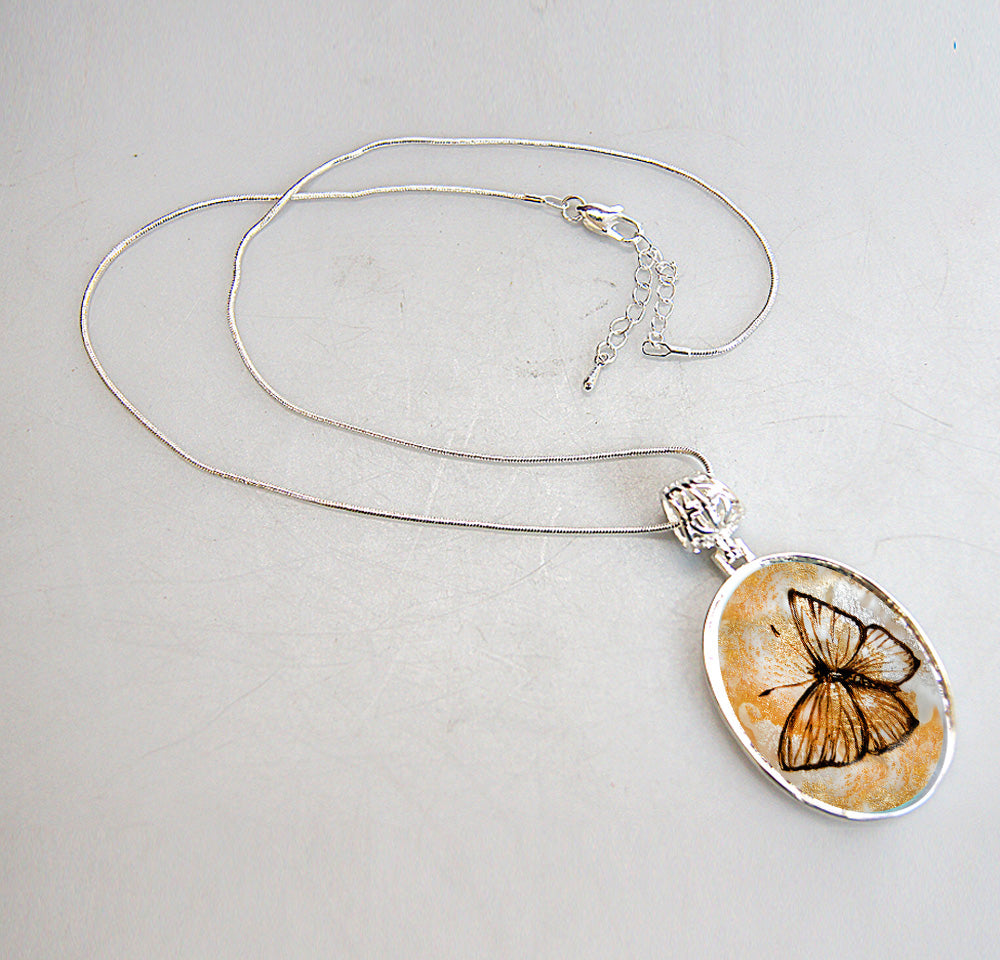 A silver necklace with a pendant featuring a butterfly design.