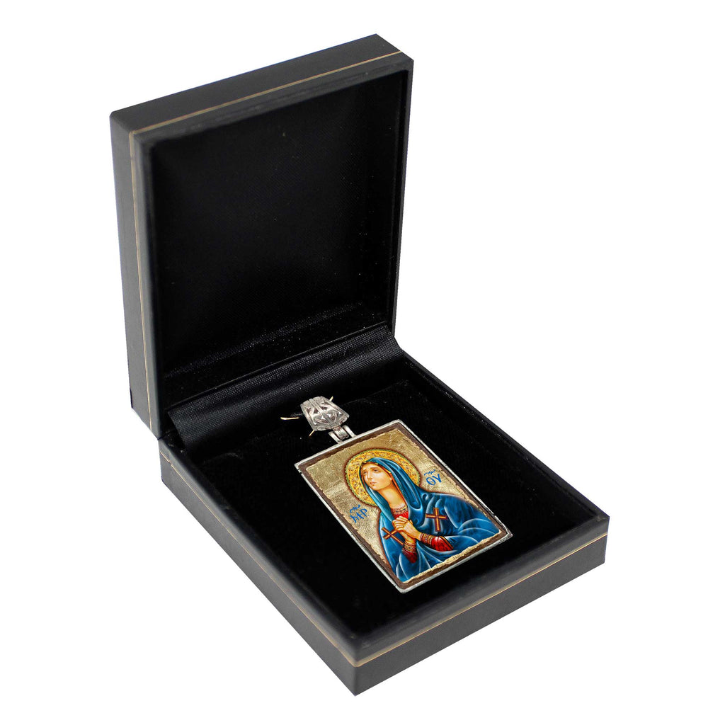 a black box containing a religious icon, possibly a religious pendant or emblem, with a gold-colored metal frame.