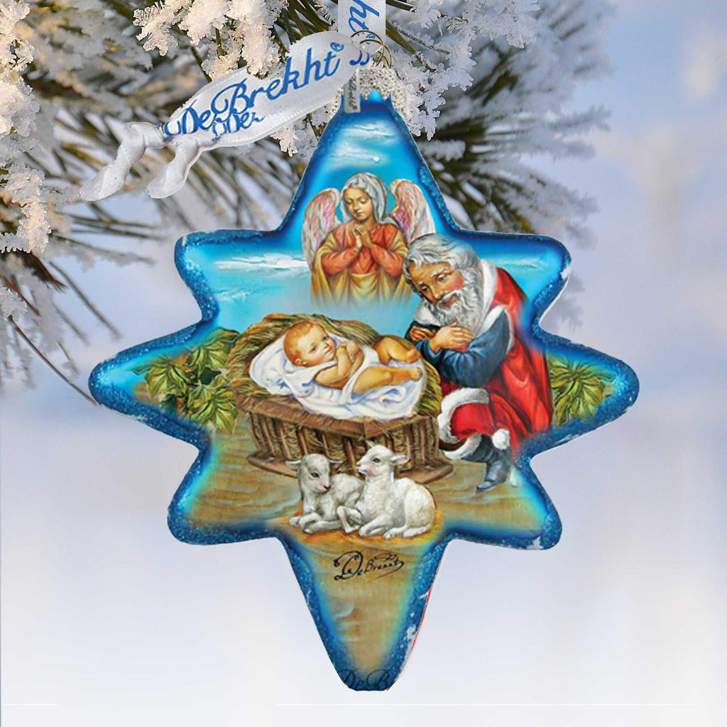 A blue star-shaped ornament with a nativity scene depicting a baby Jesus, a man, and two angels, hanging on a tree branch.