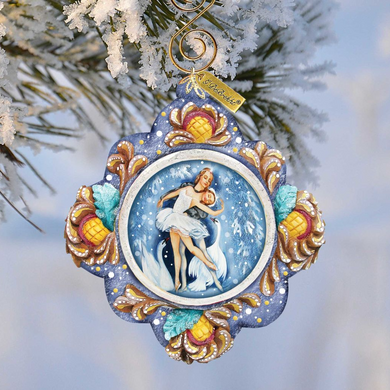 A decorative ornament featuring a woman in a white dress dancing, surrounded by snowflakes and pine branches.