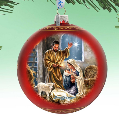 A red Christmas ornament with a painting of a nativity scene, featuring a man, a woman, and a baby.