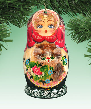 A colorful, intricately painted nesting doll ornament with a cat design, hanging on a tree branch.