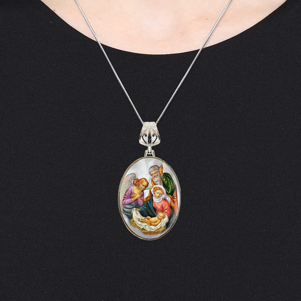 A silver necklace with a pendant featuring a religious scene.