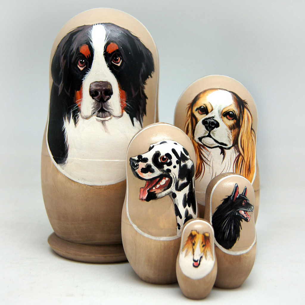 A set of wooden dolls depicting various dog breeds, including a black and white dog, a brown and white dog, and a black and white dog.