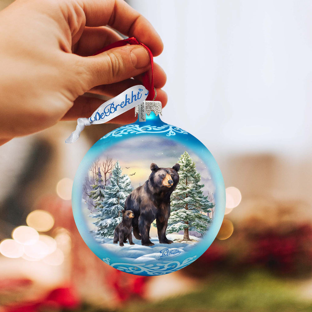 a hand holding a christmas ornament with a picture of a bear