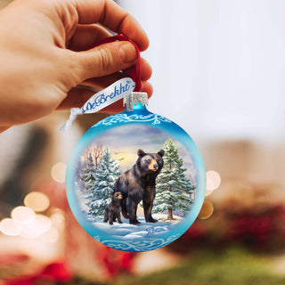 a hand holding a christmas ornament with a picture of a bear