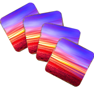 four square coasters with vibrant sunset scenes printed on them.