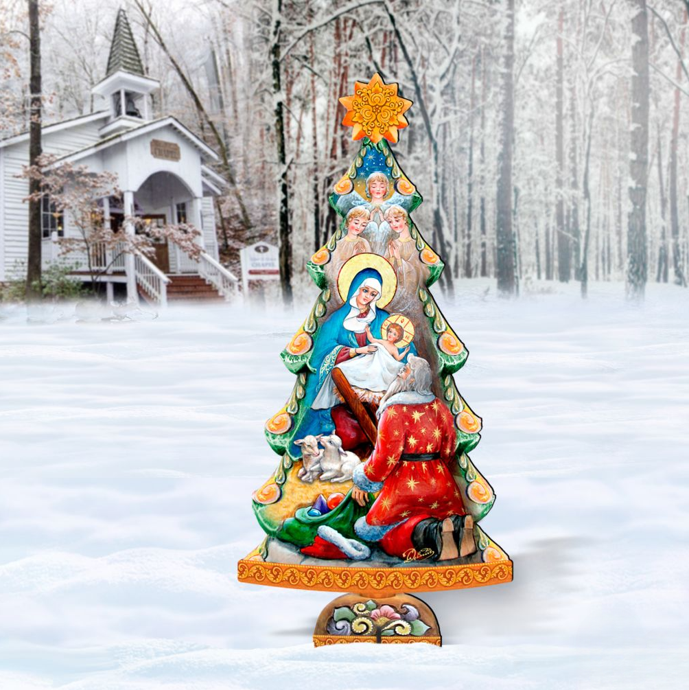 A Christmas tree decorated with religious imagery stands in a snowy landscape, with a white building and trees in the background.