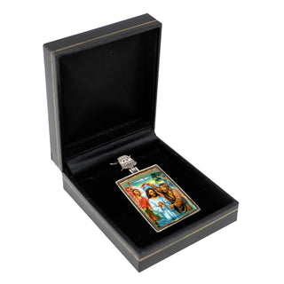 a pendant with a religious scene, displayed in a black jewelry box.