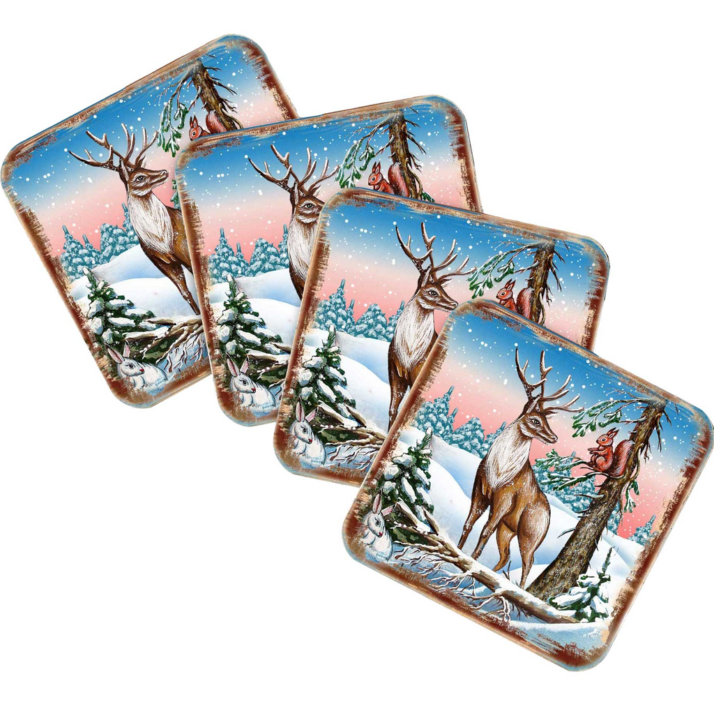 A set of four square coasters featuring a winter scene with a deer, snow, and pine trees.