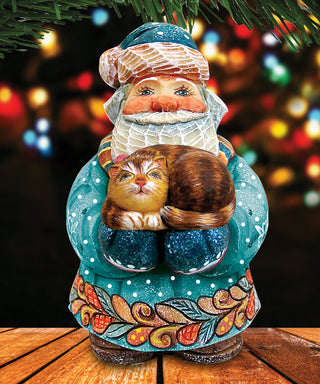 A colorful ceramic Santa Claus figurine holding a cat, set against a blurred background of colorful lights.
