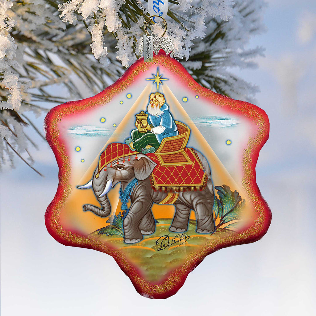 A decorative ornament featuring a man riding an elephant, with a star-shaped design and a snowy background.