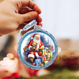 a hand holding a christmas ornament with a picture of santa