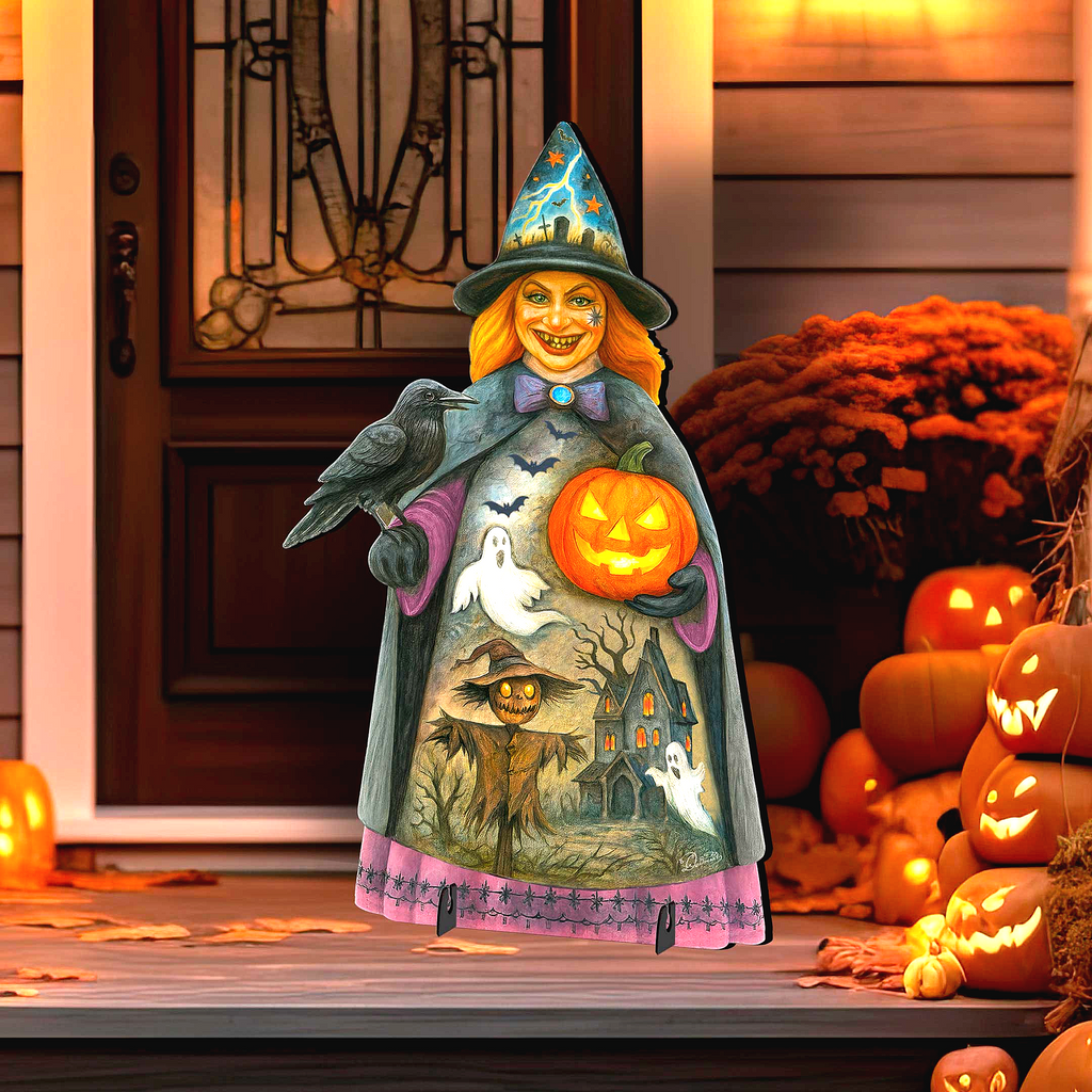 A Halloween-themed cardboard cutout of a witch holding a carved pumpkin and a bird stands on a porch surrounded by carved pumpkins and a gourd.