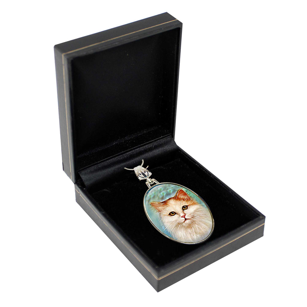 A black jewelry box containing a silver pendant with a picture of a cat on it.