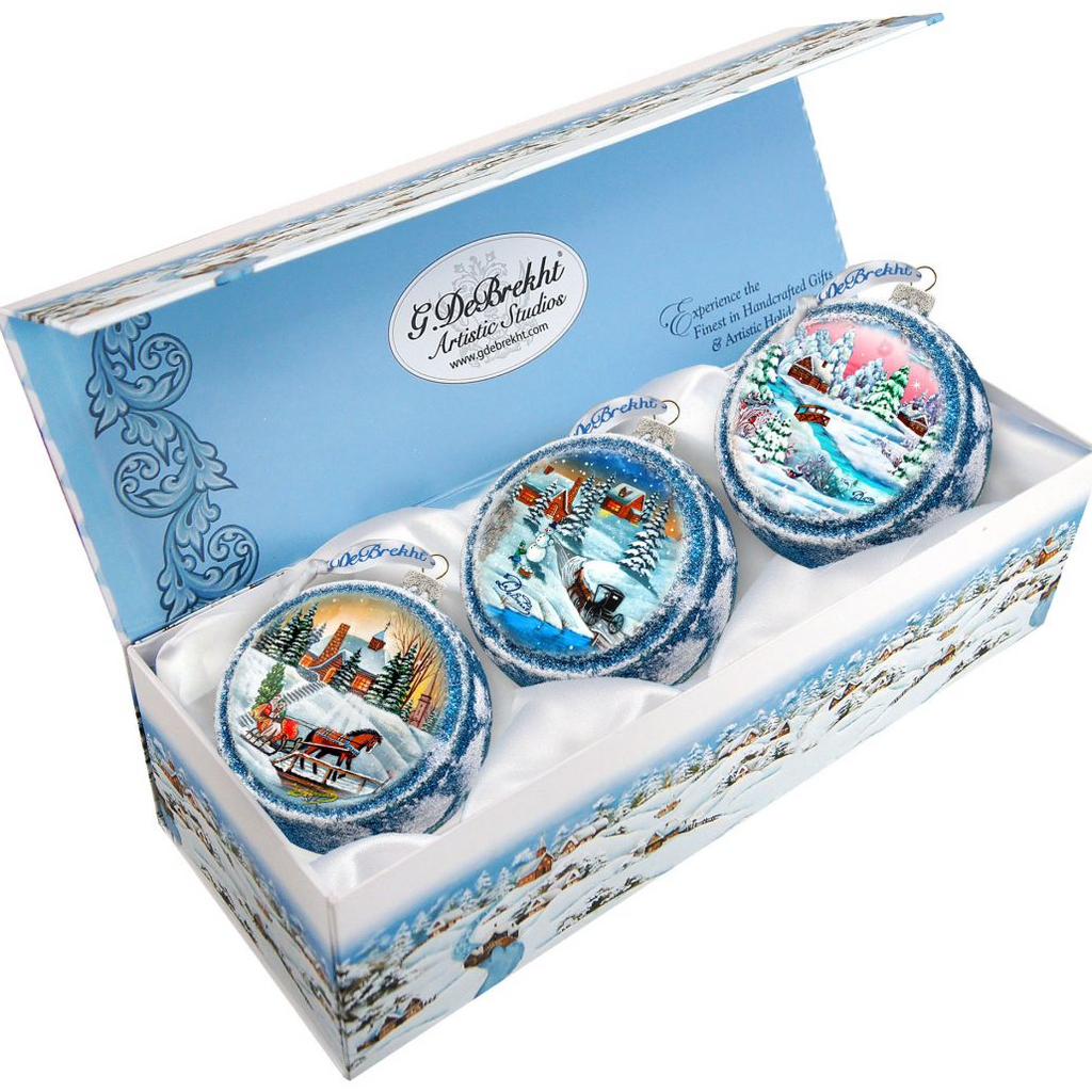 A set of three decorative Christmas ornaments in a blue box, each depicting a different winter scene.