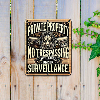 a square sign with a dog's head and two security cameras, mounted on a wooden fence.