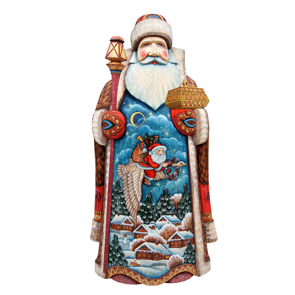 A colorful and detailed wooden carving of Santa Claus, with intricate designs and patterns depicting a winter scene with houses, trees, and a flying sleigh.