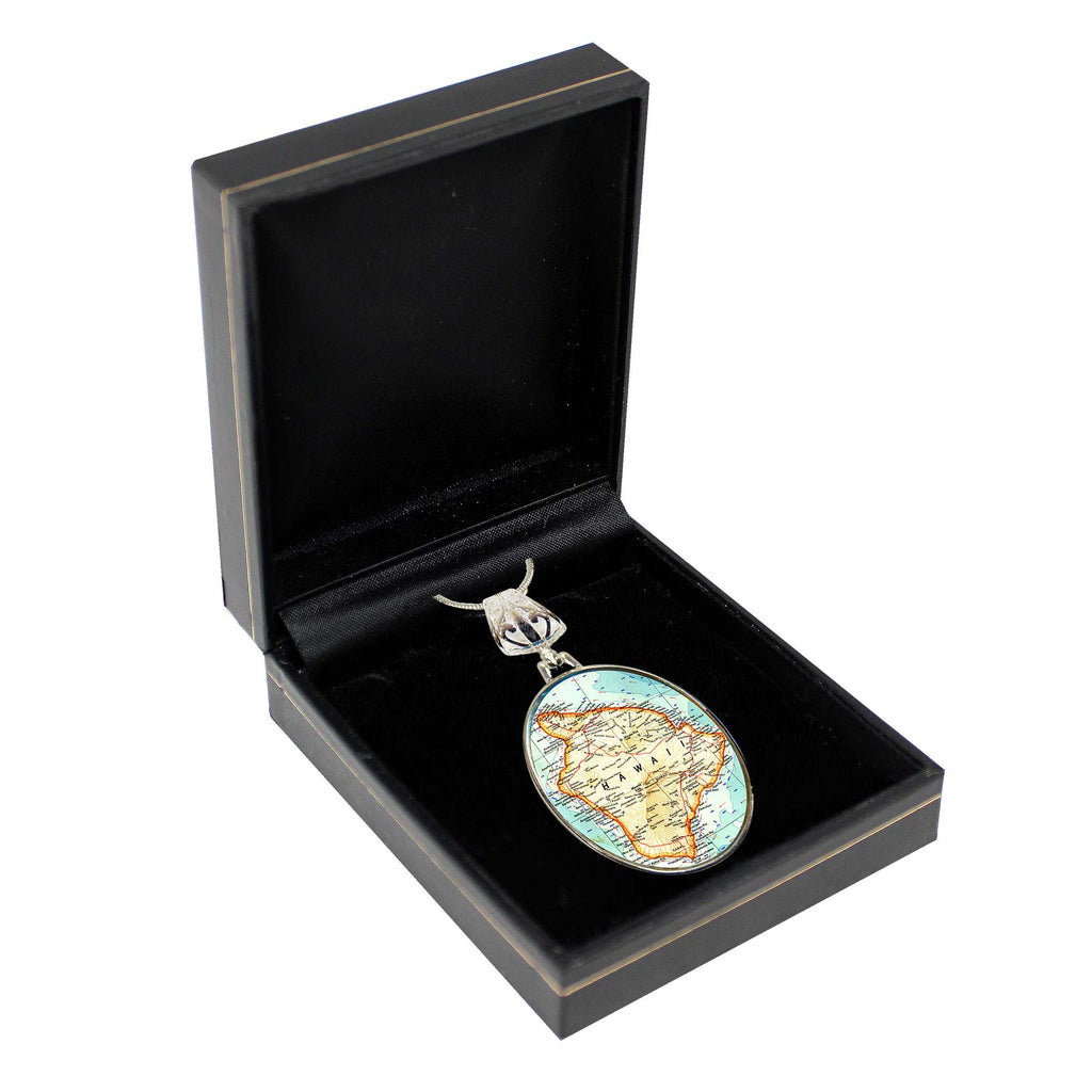 a black jewelry box containing a decorative oval-shaped charm with a map of the world on it.