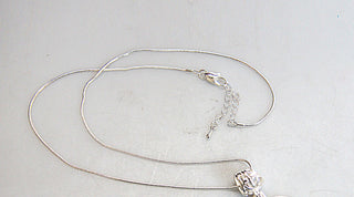 A silver necklace with a pendant is shown in the image.