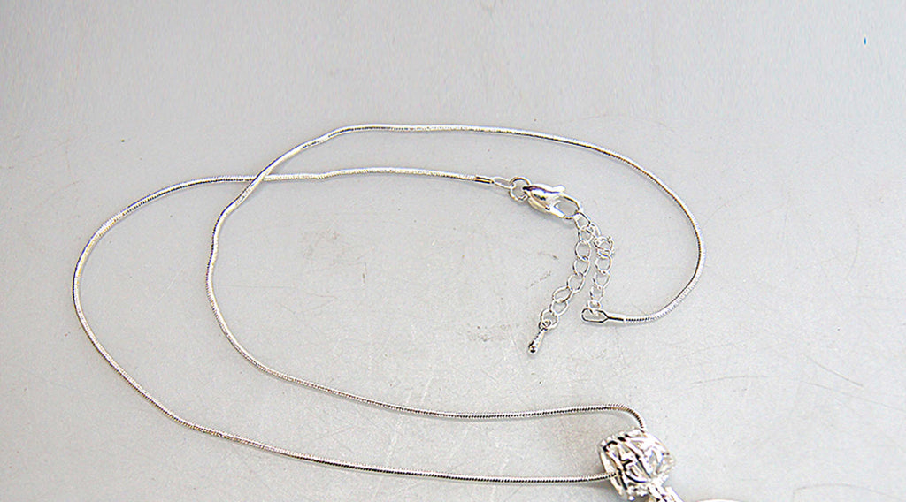 A silver necklace with a pendant is shown in the image.