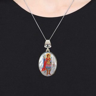 A silver necklace with a pendant featuring a religious icon of a saint.