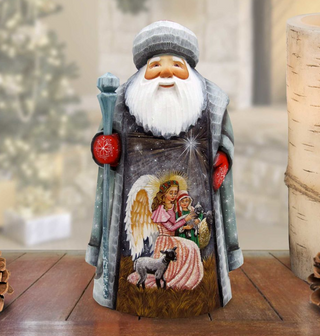 A wooden Santa Claus figurine with a white beard and hat, holding a blue staff and a red mitten, standing on a wooden surface.